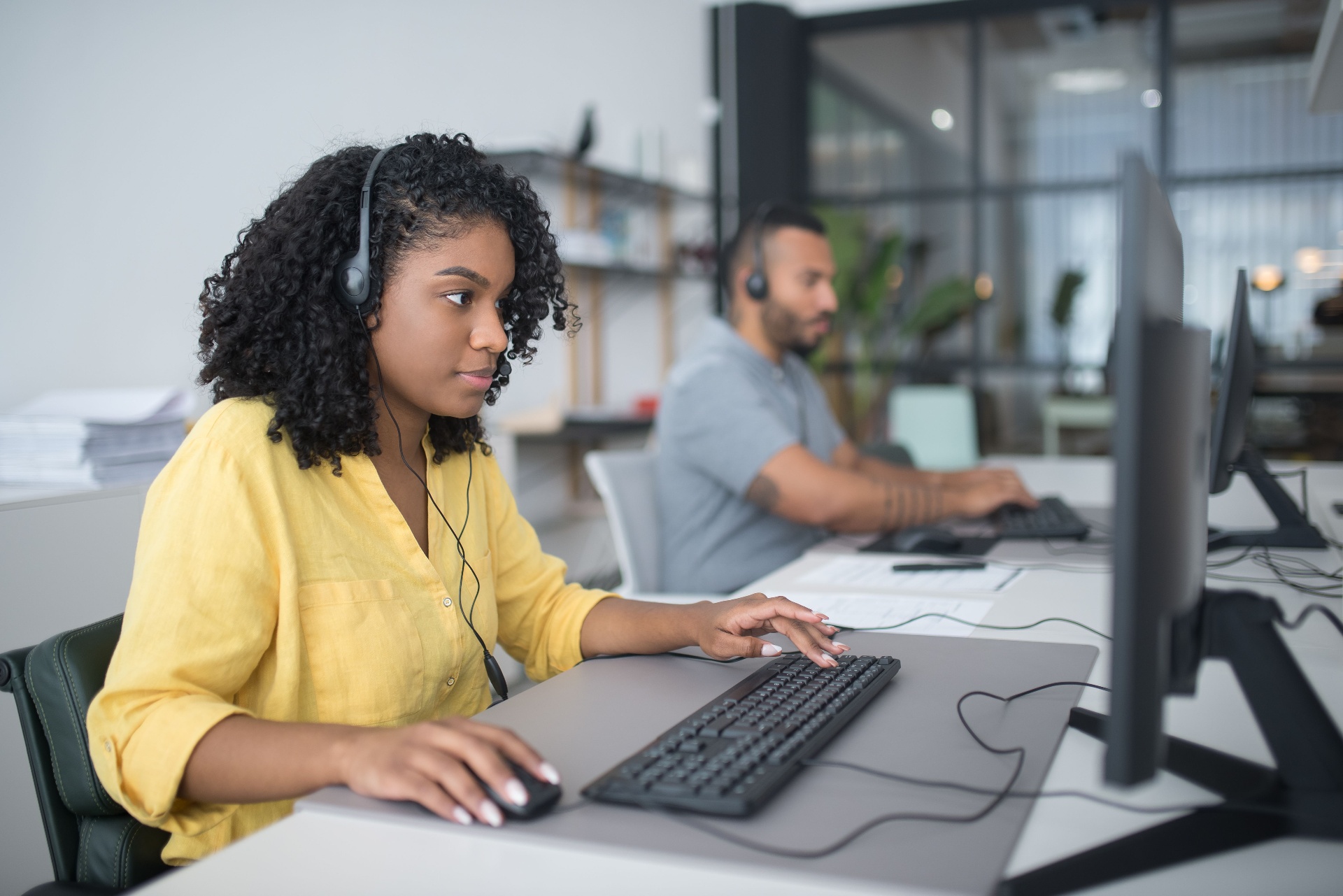 Home service CSRs wearing headsets and answering calls at a shared office workstation.
